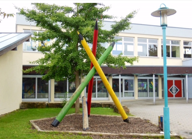  Die Birkenbachschule Kirchardt hinter symbolischen Buntstiften aus Holz - das Bild wird mit Klick vergrößert 
