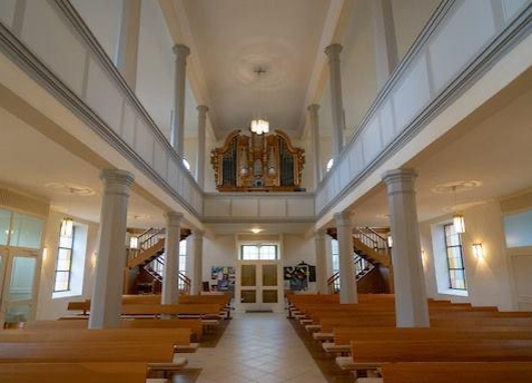  Innenansicht Heilig-Kreuz-Kirche, Blick auf Reihen mit dem Holzbänken und auf der Empore die Orgel. Das Bild wird mit Klick vergrößert 